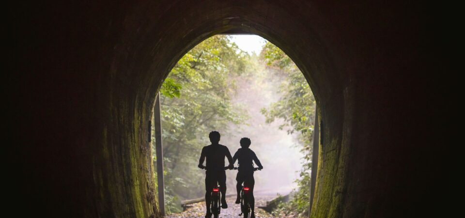 Cyclists biking through Spooner's Tunnel on Great Taste Trail